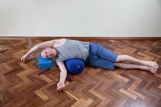 a man laying on top of a blue ball in the middle of a wooden floor