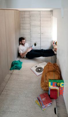 a man sitting on the floor reading a book in a room with bookshelves