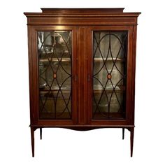 a wooden cabinet with glass doors on the top and bottom shelves, in front of a white background