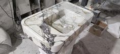 a marble sink sitting in the middle of a room filled with boxes and other items