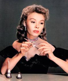 a woman sitting at a table with two pairs of scissors in her hands