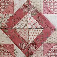 a pink and white patchwork quilt with floral designs on it's sides,