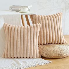 two pillows on a bed next to a wicker basket and table with a white blanket