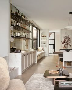 a living room filled with furniture next to a kitchen and dining room table in front of a large window