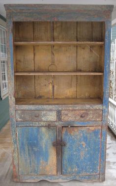 an old wooden cabinet with blue paint on the front and side doors, sitting in a porch