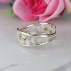 Flowers silver ring meticulously crafted using hand picked flowers and fully cured UV resin. The white silver band is inspired by the graceful charm of Boho jewelry. This Boho band ring is a perfect meaningful gift for a beloved woman, and as a pampering gift for yourself. The jewelry is very flattering, lightweight, comfortable to wear as jewelry for everyday use and impressive as jewelry for a special occasion. Each piece is individually crafted to order, ensuring a unique touch, with subtle variations that make every piece truly one-of-a-kind. Elevate your style with this exceptional jewelry- a wearable piece of art designed for your enjoyment. Purchase now for an exquisite blend of nature and craftsmanship. Special Features: - Handmade with Natural white Lobularia flowers, fully cured Silver Flower Rings For Gift, Silver Flower Rings With Adjustable Fit, Silver Flower-shaped Rings For Gift, Delicate Silver Open Ring Jewelry, Dainty Handmade Silver Flower Ring, White Sterling Silver Jewelry With Pressed Flowers, Silver Open Ring Flower Design For Anniversary, Delicate Silver Round Flower Ring, Handmade Open Band Rings For Wedding