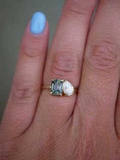 a woman's hand with a blue manicured nail polish and an engagement ring