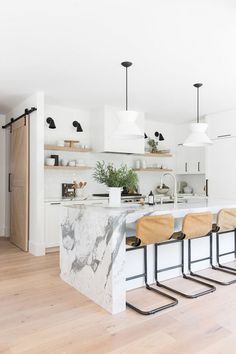 a kitchen with marble counter tops and stools