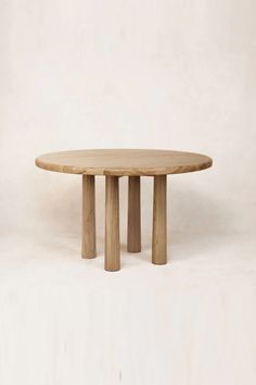 a round wooden table sitting on top of a white floor