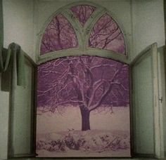 an open window with a tree in the snow