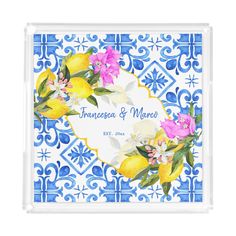 a blue and white tile with lemons, flowers and leaves on the front of it