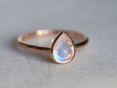 a rose gold ring with a rainbow colored tear shaped stone on it's side