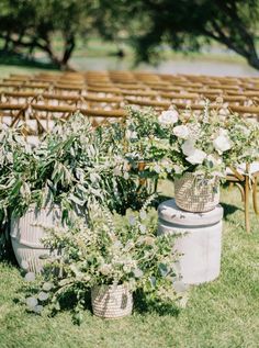 two vases filled with flowers sitting on top of grass next to rows of chairs