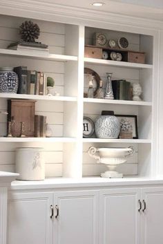 a white bookcase filled with lots of books and vases on top of it