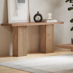 a wooden table sitting on top of a white rug next to a potted plant