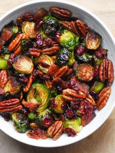 a bowl filled with brussel sprouts and pecans on top of a table