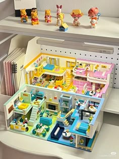 a toy house is shown with other toys on the shelf in front of it, including figurines and books