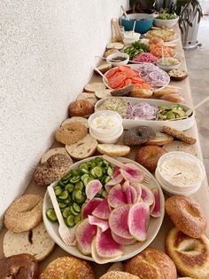 a long table filled with lots of different types of sandwiches and bagels on it