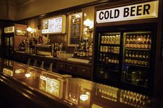 an old fashioned bar with beer bottles on the shelves and lights at the end of it