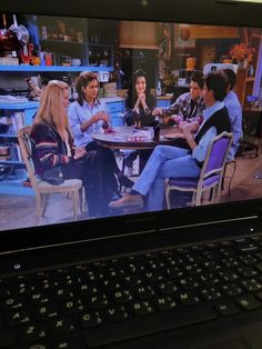 an open laptop computer sitting on top of a table with the tv show friends in front of it