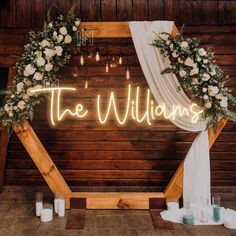 the wedding sign is lit up with flowers and greenery as well as candles in front of it