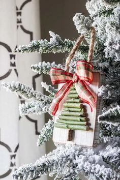 a christmas tree ornament hanging from the top of a pine tree with red and white ribbon