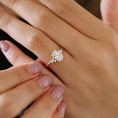 a woman's hand holding an engagement ring with a diamond on it and the other hand