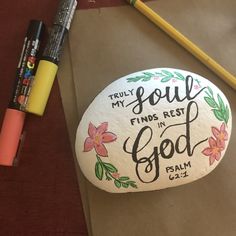 a rock that says, truly my soul finds rest in god's rim with flowers and leaves painted on it