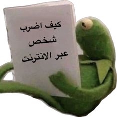 the kermie frog is holding up a sign with arabic writing in front of it