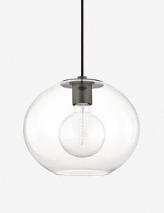 a clear glass light fixture hanging from a black ceiling hook on a white wall behind it is an object that appears to be suspended in the air