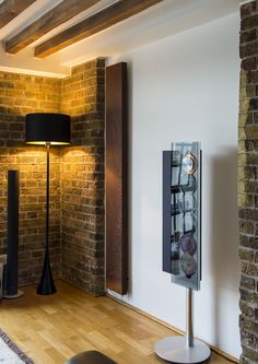 a room with a brick wall and wooden flooring next to a lamp on a stand