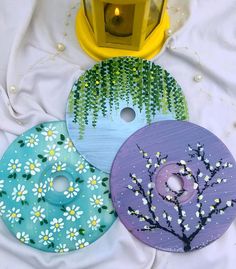 three painted discs sitting next to each other on a white sheet with a yellow light in the background