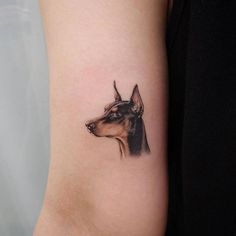 a small dog tattoo on the right inner arm and shoulder, with an image of a dog's head