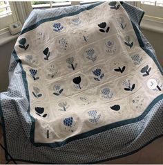 a blanket that is sitting on top of a bed with blue and white flowers in it