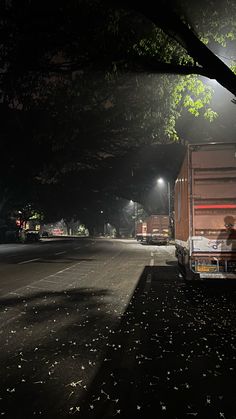 the truck is parked on the side of the road at night with its lights on