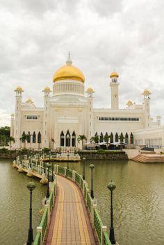 a large white building with a yellow dome on it's roof next to a body of water