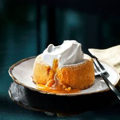 a dessert with whipped cream and caramel sauce on a plate next to a fork