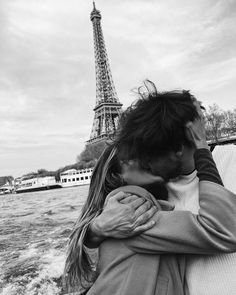 a man and woman kissing in front of the eiffel tower on a boat