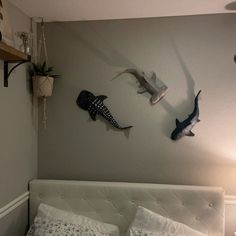 a bed with white sheets and pillows next to two wall mounted shark sculptures on the wall