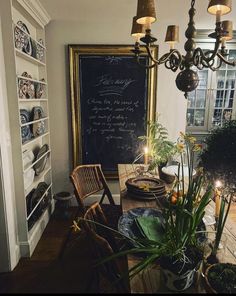 a dining room with a chalkboard on the wall and potted plants next to it