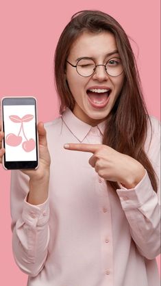 a woman in glasses pointing at her cell phone with an image of cherries on the screen