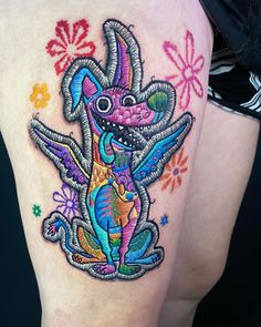 a woman's thigh with a colorful tattoo design on her leg and an animal in the center