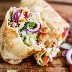 a burrito filled with lots of veggies on top of a wooden cutting board