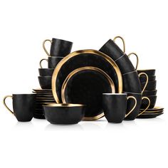 black and gold dinnerware set with matching cups, saucers and spoons on white background