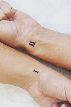 two people with matching tattoos on their arms, one is holding the other's hand