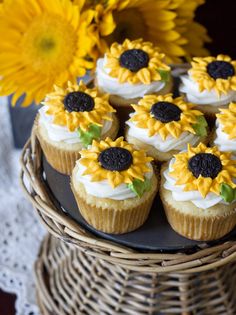 cupcakes with sunflowers on them sitting in a wicker basket