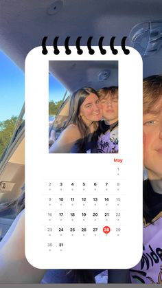 a calendar is hanging in the back seat of a car with two women and one man