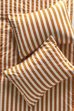 an orange and white striped bed spread with two pillow cases on top of each other