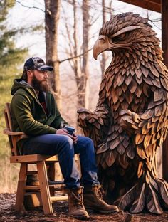 a man sitting on a wooden chair next to a large bird statue in the woods