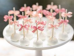 cake pops with pink bows and white chocolates on a plate in the shape of flowers